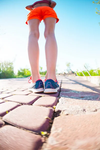 Female feet in sneakers. The woman before jogging. Legs in athletic shoes. Morning running. Active lifestyle. The girl is training. Girl in shorts.