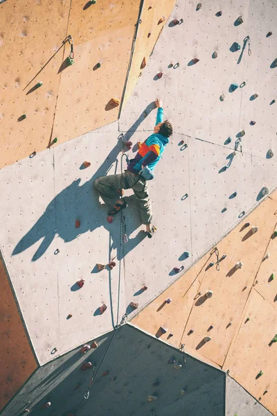 一个登山者在人工救灾 一个人爬上爬墙 在一条街头攀岩墙上训练 比赛准备 — 图库照片