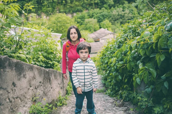 A boy and his mother are walking in the old town. A woman travels with her son in historical places. The child is walking along the old paving stones. Tourist places of Ukraine.