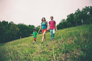 Çocuklu bir kadınla hiking gider. Kadın kollarından oğulları aldı. Aile ile seyahat. Çocuk ile kardeşi ve annesi ormanda yürür. Sırt çantaları ile yürüyüş.
