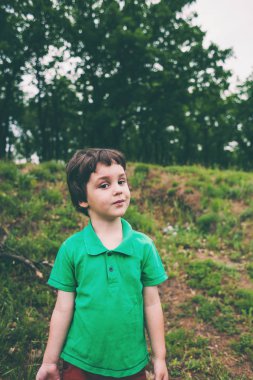 Bir çocuk portresi. Çocuk parkta yürüyor. Ormanın içinde şirin çocuk.