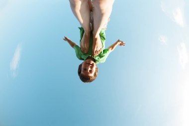 Çocuk bir uçak gibi annemin bacaklarına uçar. Çocuk gökyüzüne karşı. Çocuk ve anne doğada Yoga nişanlandık. Bir kadın oğlunu eğlendirir.