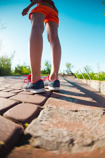 Female feet in sneakers. The woman before jogging. Legs in athletic shoes. Morning running. Active lifestyle. The girl is training. Girl in shorts.