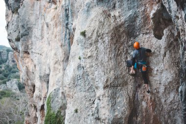 Kasklı bir adam kayaya tırmanıyor. Doğaya tırmanmak. Spor salonu açık havada. Aktif yaşam tarzı. Ekstrem sporlar. Sporcu doğal bir rahatlama ile antrenman yapar. Türkiye 'de kaya tırmanışı.