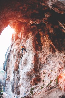Bir adam kaya tırmanıyor. Rock bir kemer şeklinde. Mağara. Fitness açık havada. Ekstrem Sporlar. Doğal bir rahatlama atlet trenlerde. Eğitim pitoresk bir yerde. Türkiye'de dağcılık.
