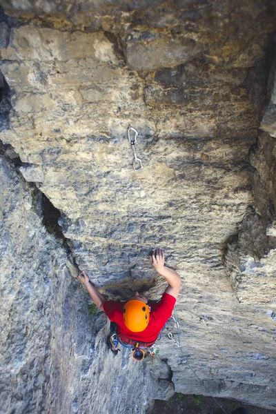 Climber in a helmet climbs up.