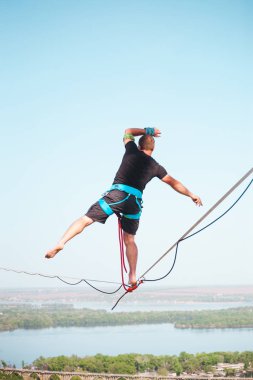Bir adam bir hat boyunca yürüyor. Dört iki yüksek binalar arasında sıkı bir çizgi izler. Highline şehrin arka planı.