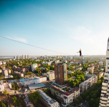 Bir adam bir hat boyunca yürüyor. Dört iki yüksek binalar arasında sıkı bir çizgi izler. Highline şehrin arka planı.