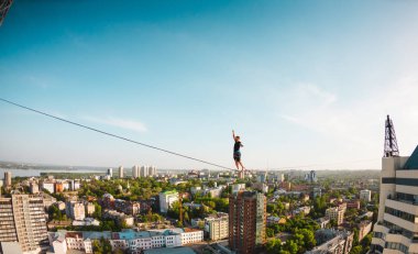 Bir adam bir hat boyunca yürüyor. Dört iki yüksek binalar arasında sıkı bir çizgi izler. Highline şehrin arka planı.