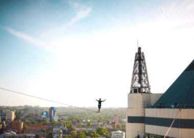 İki bina arasında uzanan bir çizgi boyunca bir adam girer. Bir adam denge irtifada yakalar. Highline şehri.