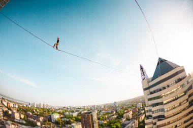 Bir adam bir hat boyunca yürüyor. Dört iki yüksek binalar arasında sıkı bir çizgi izler. Highline şehrin arka planı.