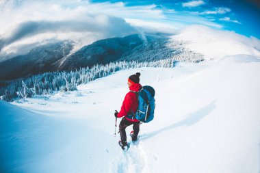 Kışın dağlarda kar ayakkabıları bir adam. Bir dağcı trekking sopa ile kar üzerinden yürür. Kış tırmanışı. Güzel gökyüzü bulutlu.