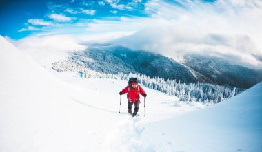 Kar ayakkabılarını ve dağlarda trekking sopalarla bir adam. Kış gezi. Güzel bir gökyüzü bulutlu karşı bir dağcı, tırmanma. Aktif yaşam tarzı. Karda dağ tırmanma.