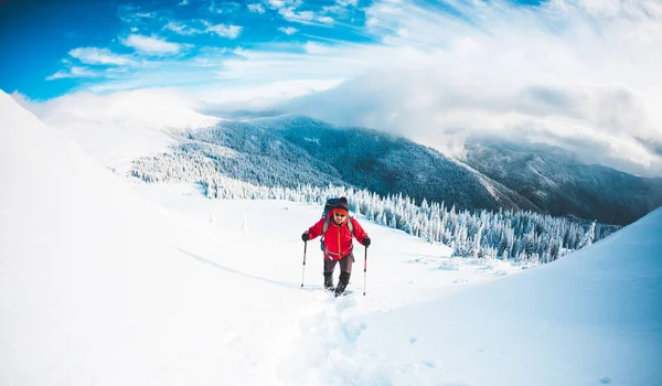 スノーシューでトレッキングのスティックを山の男 冬の旅 美しい空の雲に対する登山者の登山 アクティブなライフ スタイル 雪の中を登山 — ストック写真