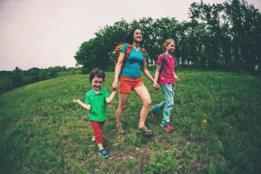 Çocuklu bir kadınla hiking gider. Aile ile seyahat. Çocuk ile kardeşi ve annesi ormanda yürür. Sırt çantaları ile yürüyüş.
