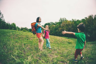 Çocuklu bir kadınla hiking gider. Aile ile seyahat. Çocuk ile kardeşi ve annesi Ormanda yürür. Sırt çantaları ile yürüyüş. Anne çocuk elini dışarı uzanır. Yardım eli.