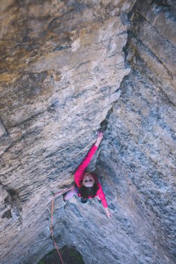 Kız rock tırmanıyor. Bir kadın zor bir tırmanış rota üstesinden gelir. Bir kaya üzerinde bir dağcı. Açık havada spor yapmak.