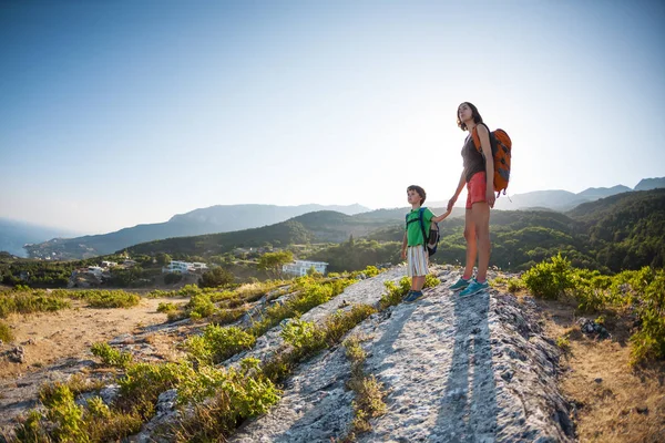 女性は子供と一緒に旅行している 山の中の母と息子 子供と一緒に山の頂上に登る リュックを背負った少年は上に登った 休暇中 — ストック写真