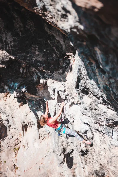 A woman climbs the rock. Climbing in nature. Fitness outdoors. Active lifestyle. Extreme sports. The athlete trains on a natural relief. Training in a picturesque place. Rock climbing in Turkey.