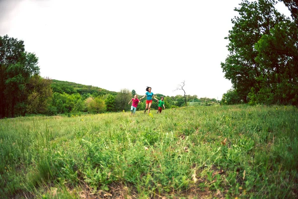 Çocuklu bir kadınla yeşil çim çalışır. Anne oğlunu elleri ve gülüyor tarafından tutar. Açık havada ailesiyle birlikte oynayan bir çocuk. Çocuk annesi ve kardeşi ile çayırlarda yürür.