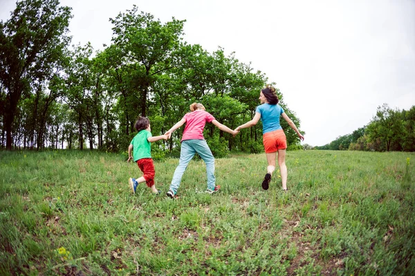 Çocuklu bir kadınla yeşil çim çalışır. Anne oğulları tarafından ellerini tutar ve çalıştırın. Açık havada ailesiyle birlikte oynayan bir çocuk. Çocuk annesi ve kardeşi ile çayırlarda yürür.
