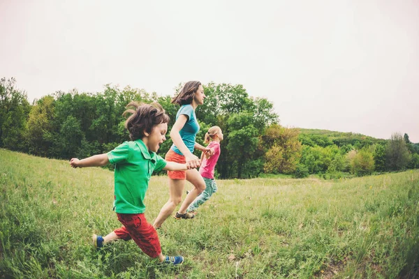 Çocuklu bir kadınla yeşil çim çalışır. Anne oğulları tarafından ellerini tutar ve çalıştırın. Açık havada ailesiyle birlikte oynayan bir çocuk. Çocuk annesi ve kardeşi ile çayırlarda yürür.