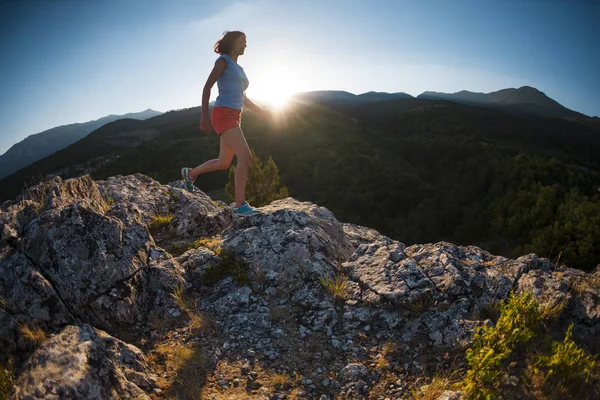 the girl runs through the mountains against the sunset. the training of an athlete in nature.