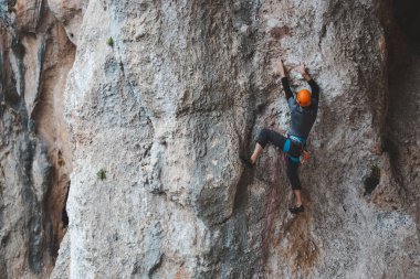 Kasklı bir adam kayaya tırmanıyor. Doğaya tırmanmak. Spor salonu açık havada. Aktif yaşam tarzı. Ekstrem sporlar. Sporcu doğal bir rahatlama ile antrenman yapar. Türkiye 'de kaya tırmanışı.