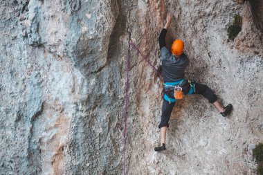 Kasklı bir adam kayaya tırmanıyor. Doğaya tırmanmak. Spor salonu açık havada. Aktif yaşam tarzı. Ekstrem sporlar. Sporcu doğal bir rahatlama ile antrenman yapar. Türkiye 'de kaya tırmanışı.