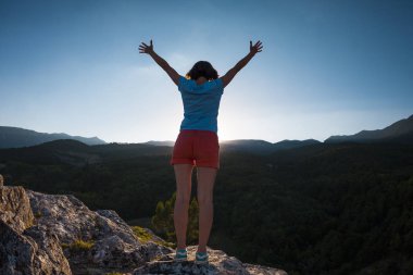 Dağın zirvesine kıza ellerini kaldırdı. Kadın için üst tırmandı ve onun başarı sevinir. Batan güneşin ışınları. Sabah güneşi selamlar.