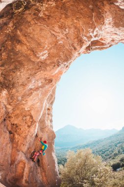 Bir kadın rock tırmanıyor. Rock bir kemer şeklinde. Mağara. Ekstrem Sporlar. Doğal bir rahatlama atlet trenlerde. Atlet zor bir tırmanış rota üstesinden gelir. Türkiye'de dağcılık.