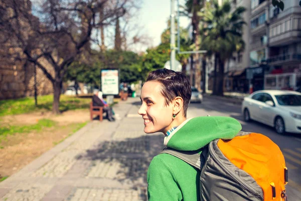 A girl with a backpack is walking around the city. The tourist inspects the sights. The woman is traveling. Portrait of a smiling brunette.
