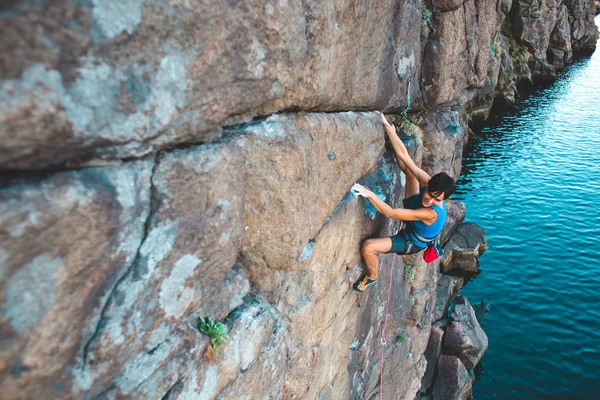 女の子の登山家は 水の上の岩を登っていきます 野外活動 極端なスポーツ — ストック写真