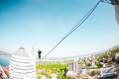 İki bina arasında uzanan bir çizgi boyunca bir adam girer. Aşırı eğlence. Yükseklik korkusu. Adam şehrin üzerinde Dengeleme.