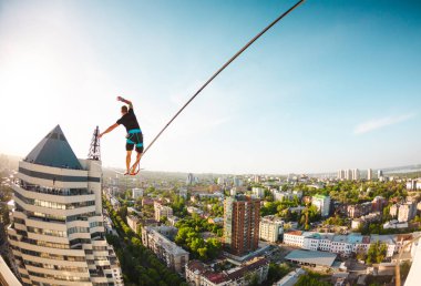 İki bina arasında uzanan bir çizgi boyunca bir adam girer. Bir adam denge irtifada yakalar. Highline şehri.