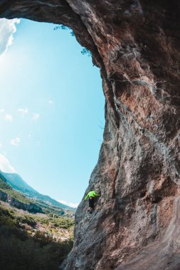 Bir adam bir dağ manzarasına karşı kayaya tırmanır. Sporcu doğal bir rahatlama ile antrenman yapar. Türkiye 'de tırmanış. Kemer şeklinde bir kaya. Mağara. Dağcı zor bir yolun üstesinden gelir..