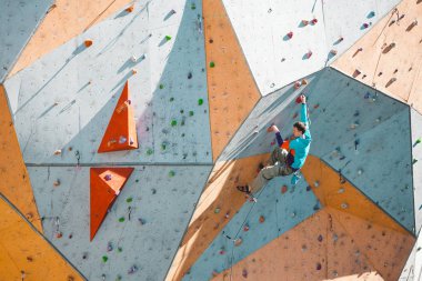 Yapay bir kabartma bir dağcı. Bir adam tırmanma duvarı tırmanıyor. Sokak tırmanma duvarı üzerinde eğitim. Yarışmalar için hazırlık. Egzersiz.