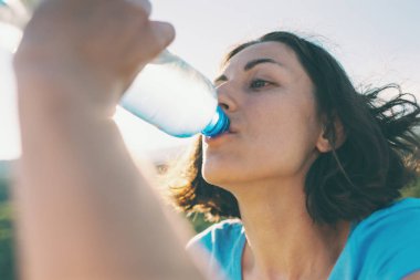 İçme suyu bir dağın tepesinde bir kadındır. Kız onun susuzluk quenches. Yorgun turistik bir plastik şişeden içer. Esmer su ağzının kenarında bir şişe tutuyor.