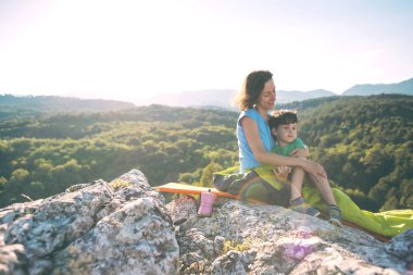 Dağın tepesinde kamp yapmak. Anne ve çocuk birlikte seyahat ediyorlar. Bir kadın ve oğlu tırmanıştan sonra dinleniyor. Uyku tulumundaki kız. Annelik kucaklaması..