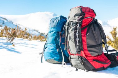 Karla kaplı dağlar ve mavi gökyüzü arka planda iki sırt çantaları. Kar üzerinde bir sırt çantası. Aktif yaşam tarzı. Kış aylarında trekking.