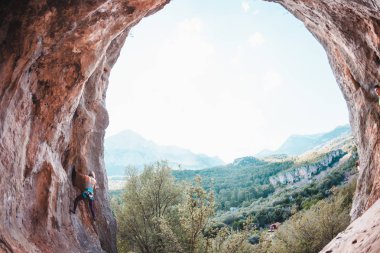 Bir kadın rock tırmanıyor. Rock bir kemer şeklinde. Mağara. Ekstrem Sporlar. Doğal bir rahatlama atlet trenlerde. Atlet zor bir tırmanış rota üstesinden gelir. Türkiye'de dağcılık.