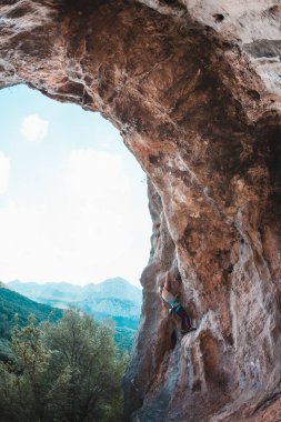 Bir kadın rock tırmanıyor. Rock bir kemer şeklinde. Mağara. Ekstrem Sporlar. Doğal bir rahatlama atlet trenlerde. Atlet zor bir tırmanış rota üstesinden gelir. Türkiye'de dağcılık.