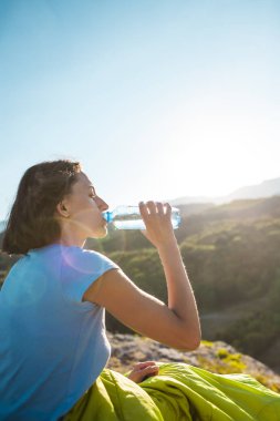 İçme suyu bir dağın tepesinde bir kadındır. Kız onun susuzluk quenches. Yorgun turistik bir plastik şişeden içer. Esmer bir uyku tulumu içinde oturuyor.