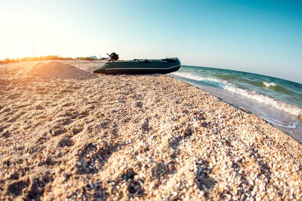 Inflatable boat on the beach. Sea coast. Beautiful sunset by the ocean. Motor boat on the shore.