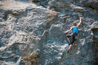 Dağcı kayaya tırmanmak için eğitim alıyor. Güçlü bir kız zor bir tırmanış rota üstesinden gelir. Aktif yaşam tarzı. Aşırı hobi. Doğa sporları için bir kadın giriyor.