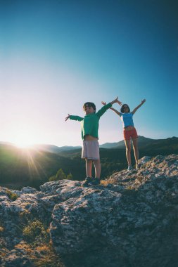 Bir çocuk annesi günbatımında bir dağın tepesinde ile. Çocuk zirveye tırmanış sahiptir. Kadın ve oğlu ellerini kaldırdı. Çocuklarla seyahat.