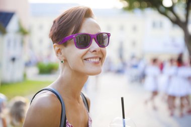 Bir kız bir saman bir içki içecekler. Bir kadın gözlük bir şehir sokak sabah kahve içiyor. Gülümseyen bir esmer bir milkshake bir plastik bardaktan içiyor..
