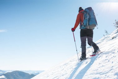 Dağcı kar ayakkabıları bir sırt çantası taşımak. Yolculuk kışın dağlarda. Doğada aşırı tatil.