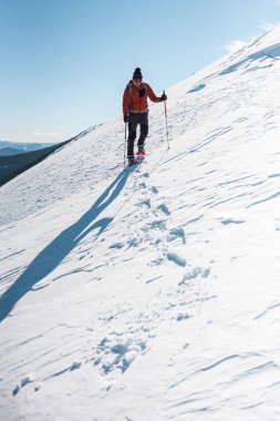 Bir adam dağın zirvesine tırmanıyor. Dağcı kar ayakkabıları bir sırt çantası taşımak. Yolculuk kışın dağlarda. Doğada aşırı tatil. Aşırı koşullarda Turizm.