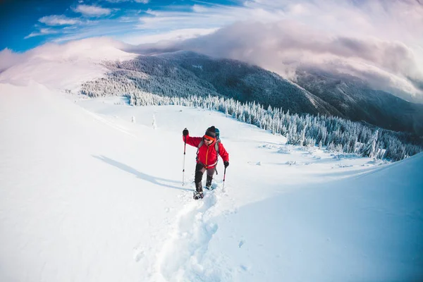 スノーシューでトレッキングのスティックを山の男 冬の旅 美しい空の雲に対する登山者の登山 アクティブなライフ スタイル 雪の中を登山 — ストック写真